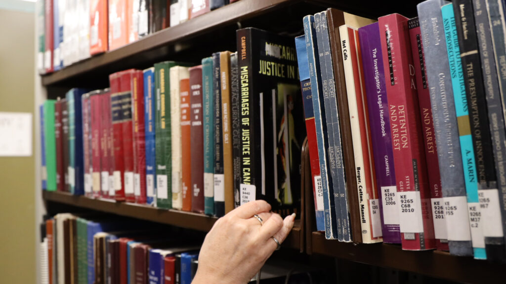 Hand grabbing a book from a shelf at the MacOdrum Library
