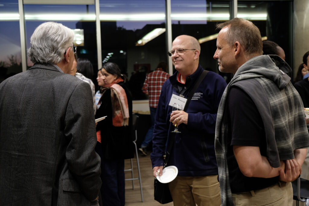 Group of people engaged in conversation at the economics alumni reception