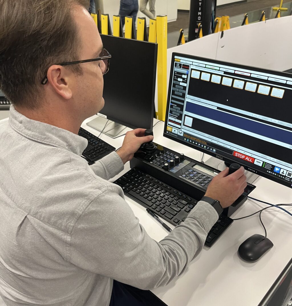 Carleton alum, Nick Simpson, sits in the Ross Video robotics lab at the control panel for Artimo, the award-winning studio robot he helped design.