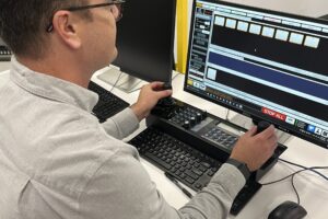 Carleton alum, Nick Simpson, sits in the Ross Video robotics lab at the control panel for Artimo, the award-winning studio robot he helped design.