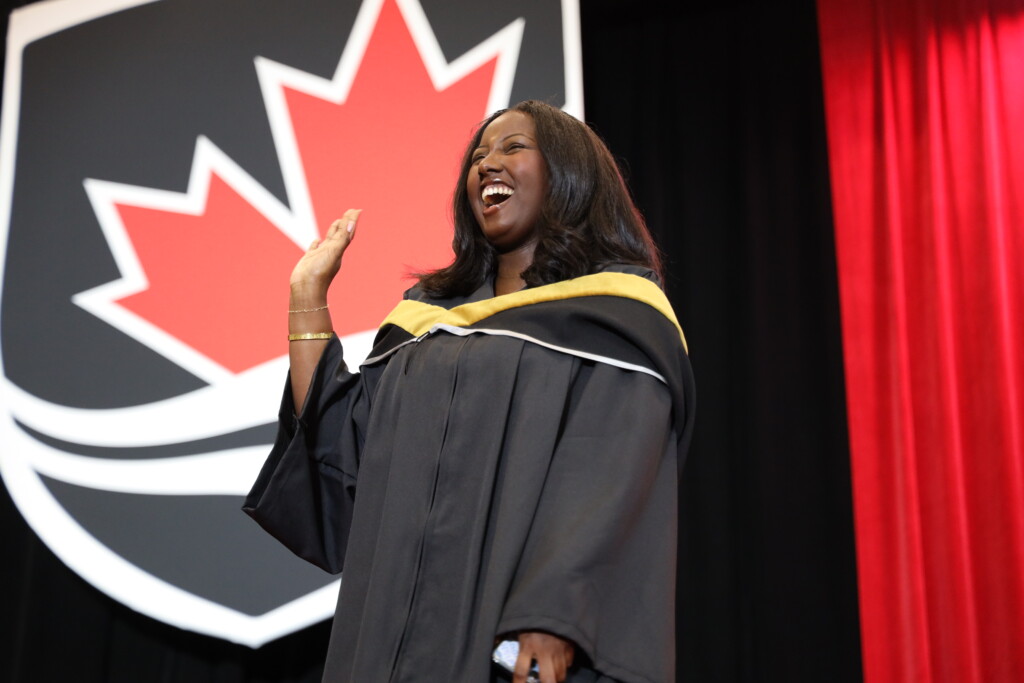 Alumni crossing convocation stage smiling and waving
