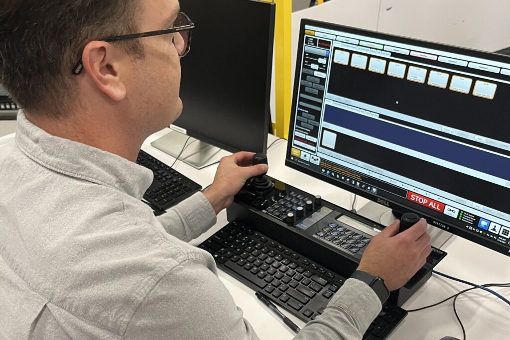 Carleton alum, Nick Simpson, sits in the Ross Video robotics lab at the control panel for Artimo, the award-winning studio robot he helped design.
