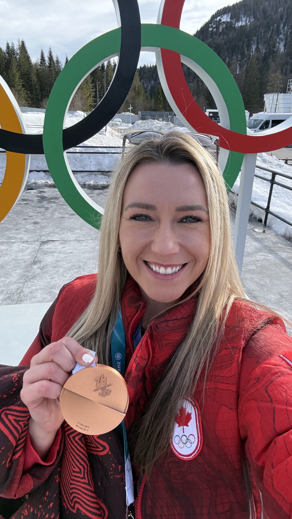 Emma Miskew with her bronze medal in front of the olympic rings