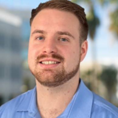 A professional headshot image of Dan Byron in a blue collared shirt. 