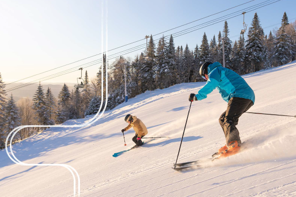 Two skiers makign their way down a snowy mountain. 
