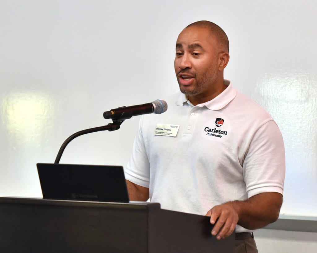a photo of Stenley Phillippe speaking into a microphone at the podium. 