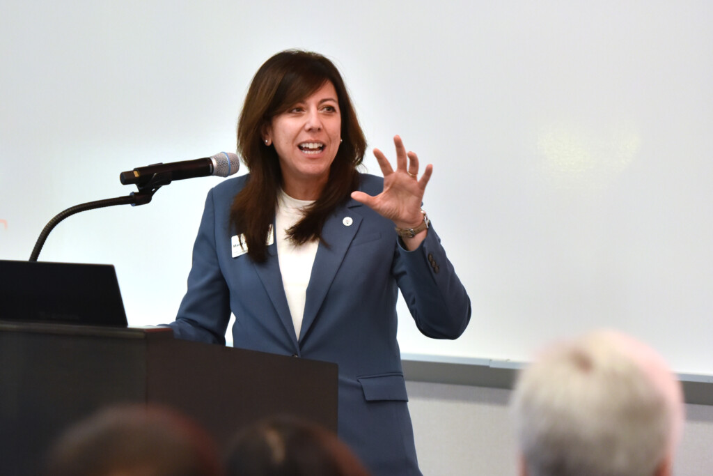a photo of dean Maria DeRosa giving a speech at a podium. 