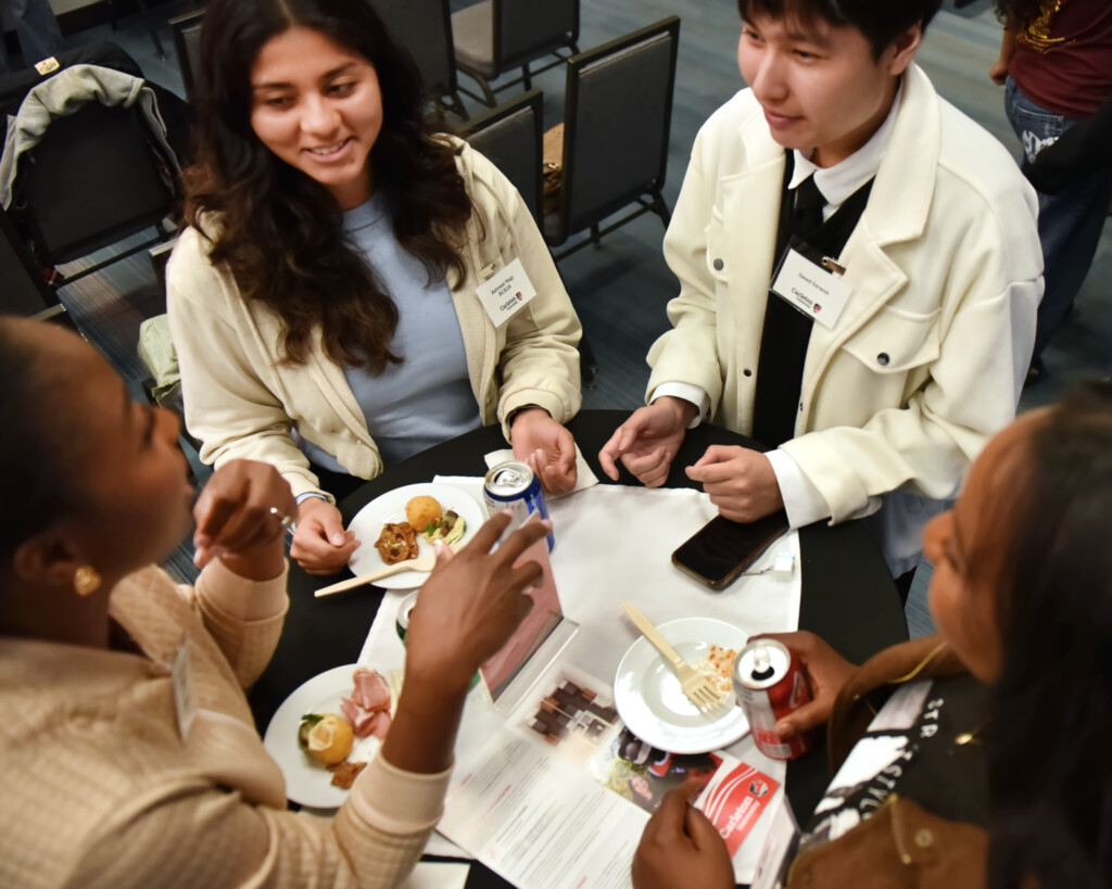 a photo of four people talking around a table