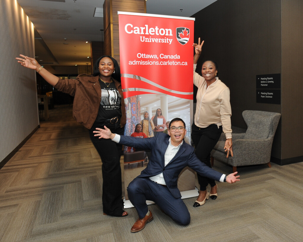 a group of three Carleton alumni in front of a banner.