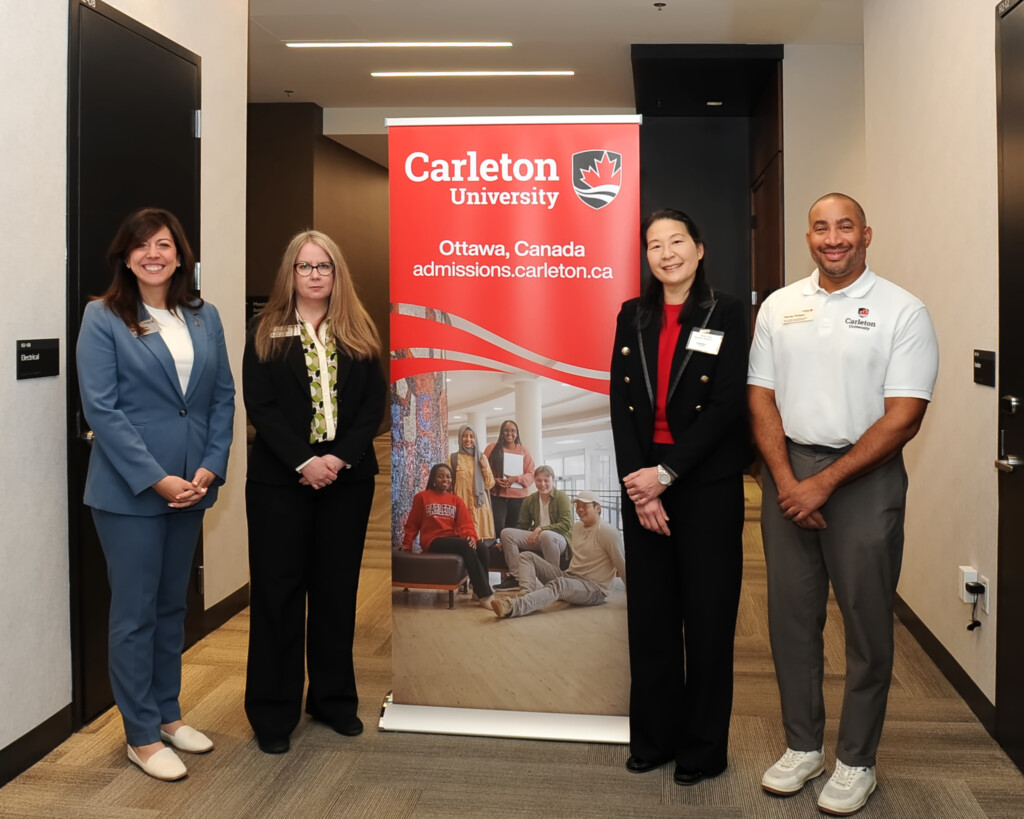A photo 4 members of Carleton's leadership team standing in front of a Carleton branded banner. 