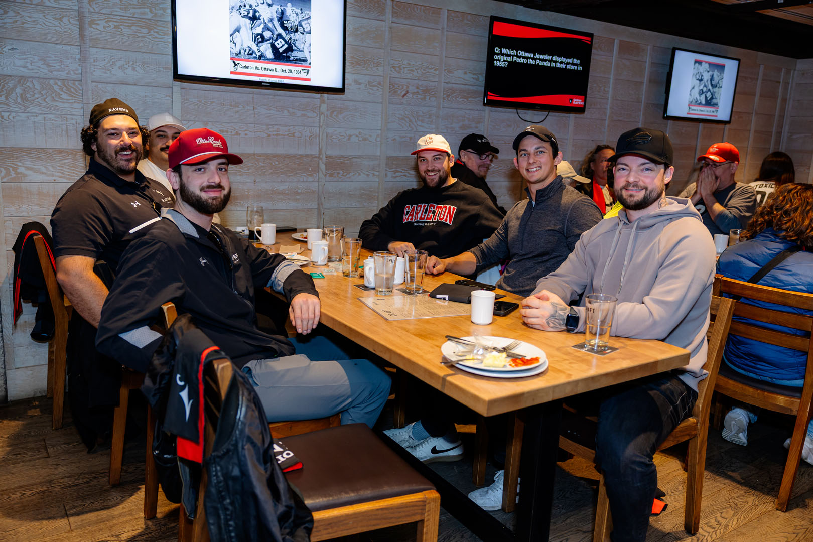 Six people sit together at a table, smiling, during the Pancaker Breakfast