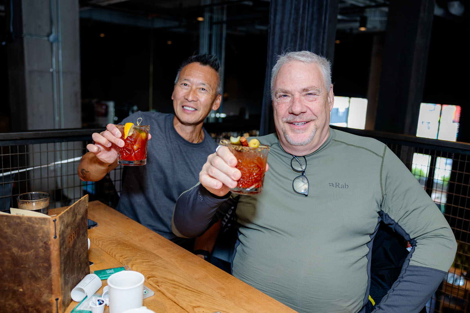 Two people hold their drinks up smiling at the Pancaker Breakfast
