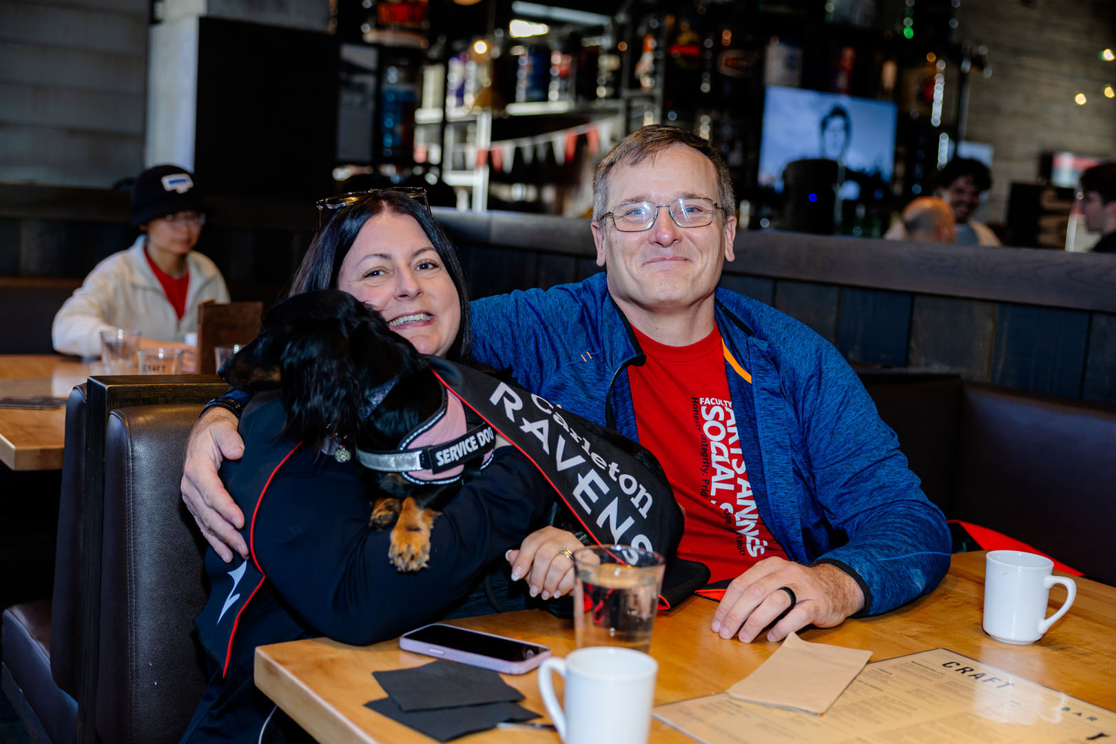 Two people and a service dog seated at a table for the Pancaker breakfast