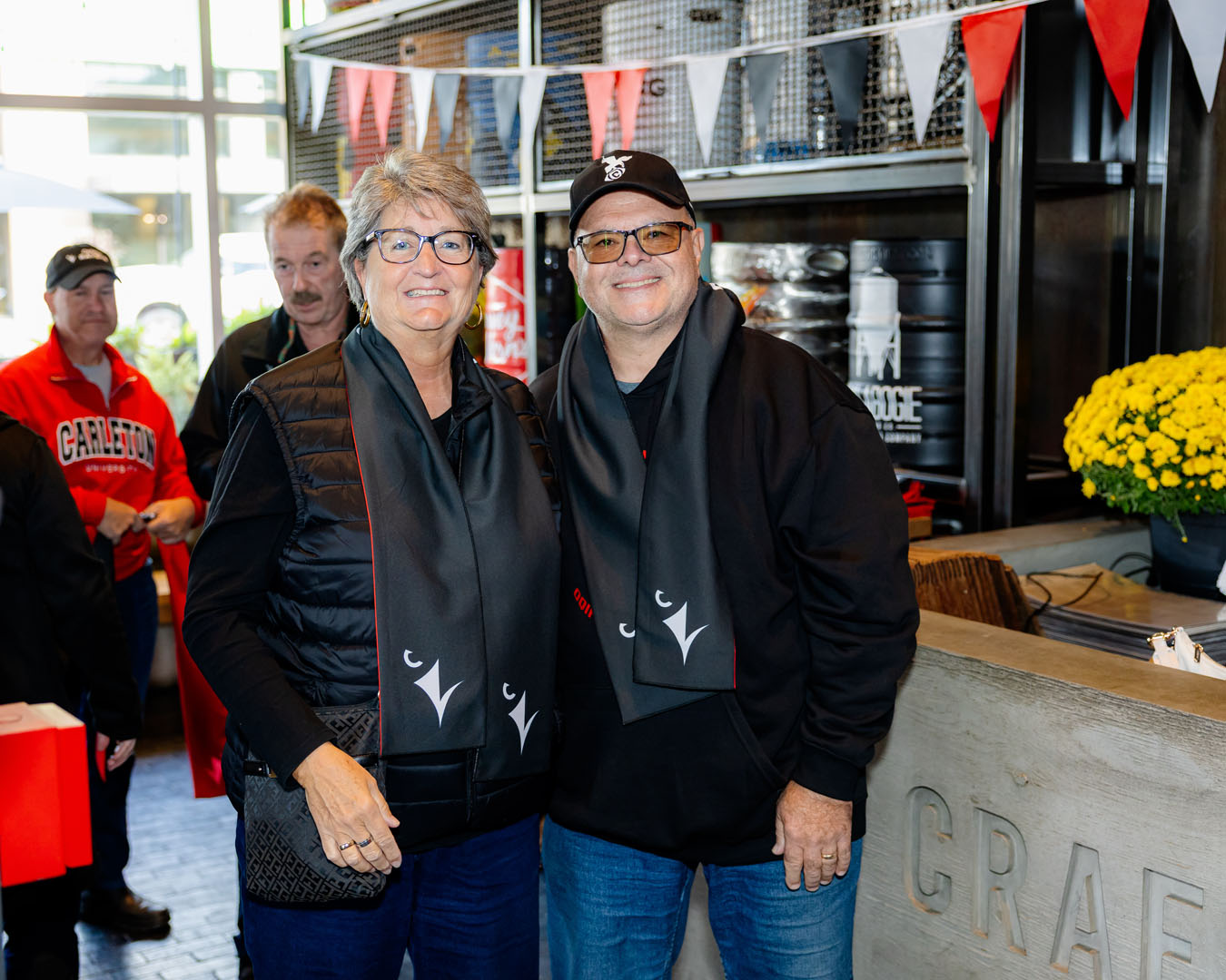 Two people smile, wearing Ravens scarves, at the Pancaker Breakfast.