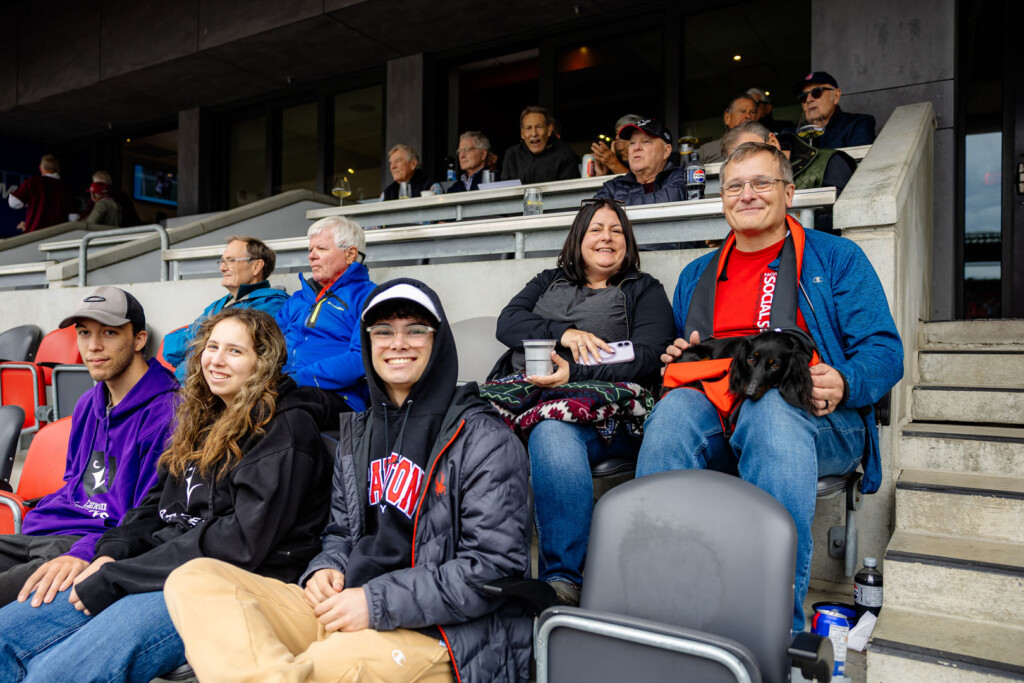 Group of people and service dog smile for a photo at Panda Game