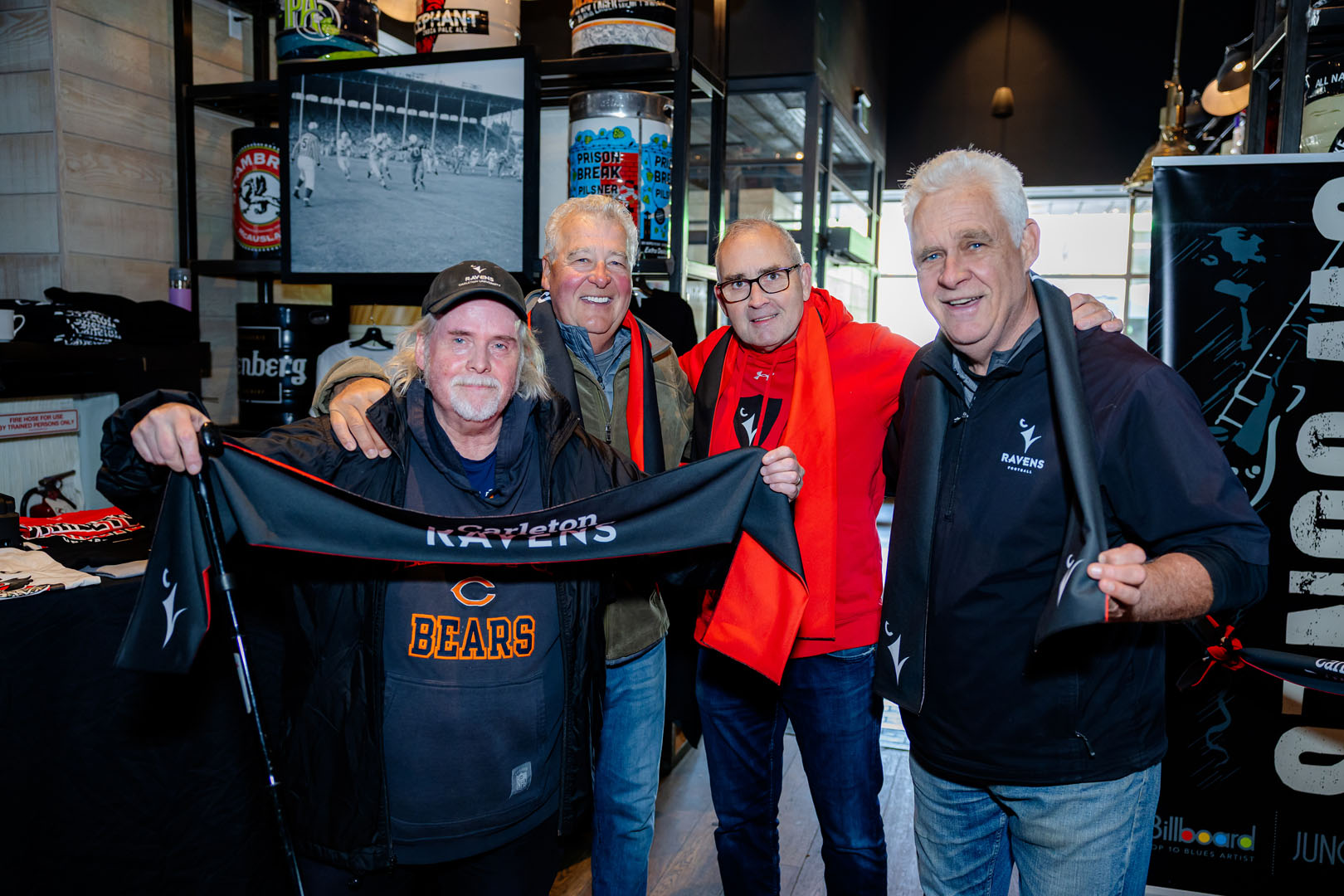 Four people smile, showing off their Ravens gear