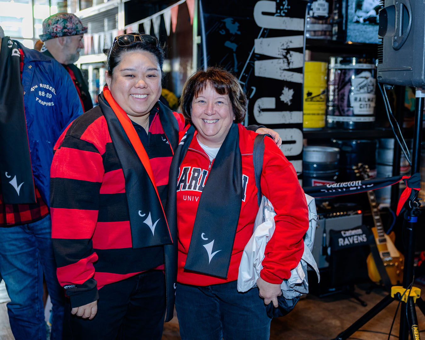 Two people smile wearing Ravens scarves