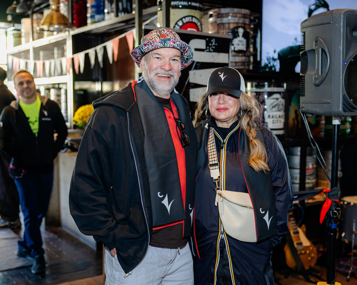 Two people smile for a photo wearing a Ravens hat and Ravens scarves.