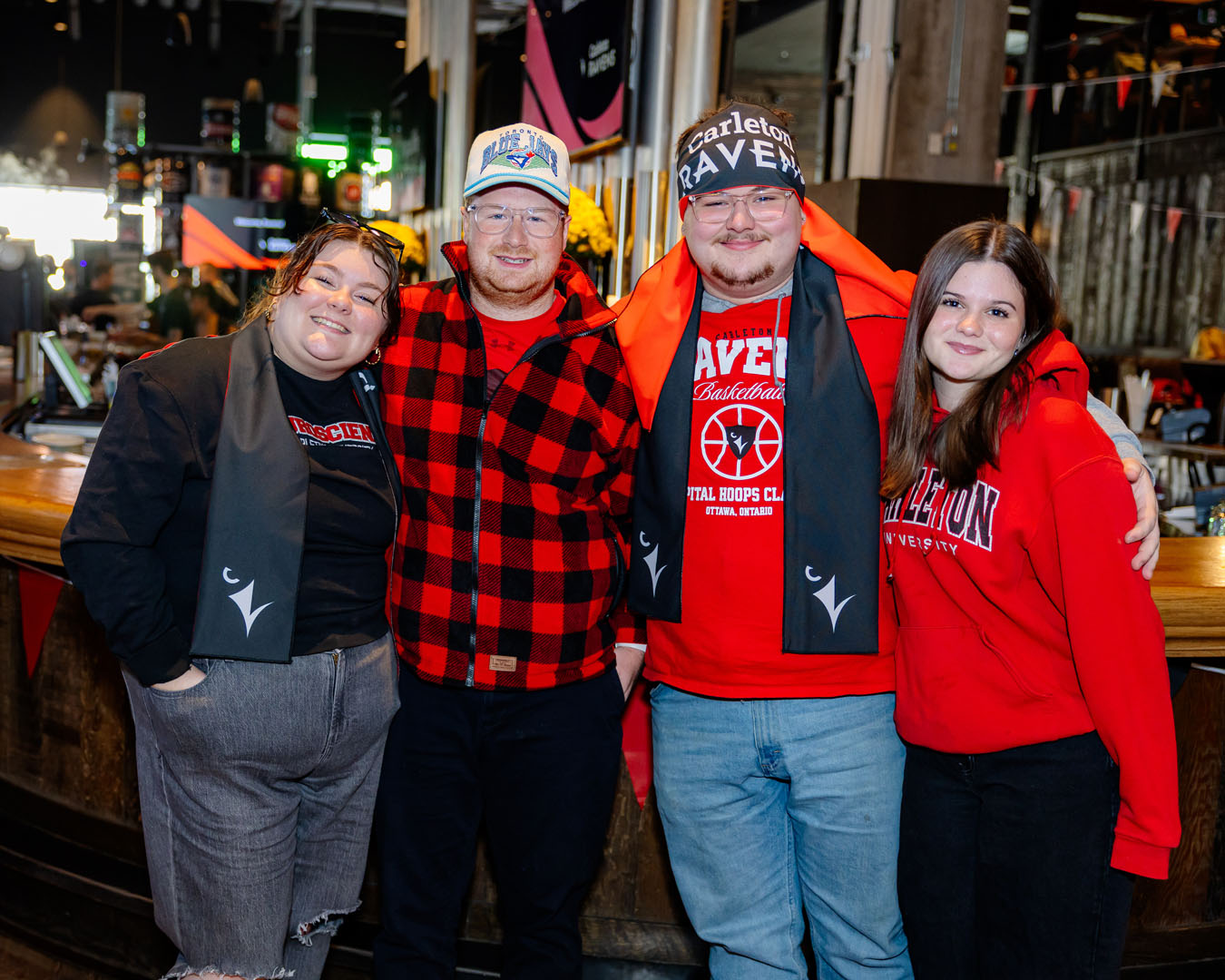 Four people wearing Carleton spirit wear smile for a photo